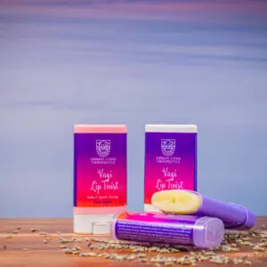 Two purple and red lip balms sitting on a table.